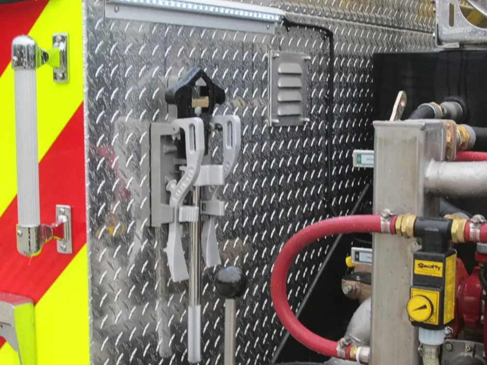 Exterior view of small fire truck showing cab, body compartments, and wheel/tire area.