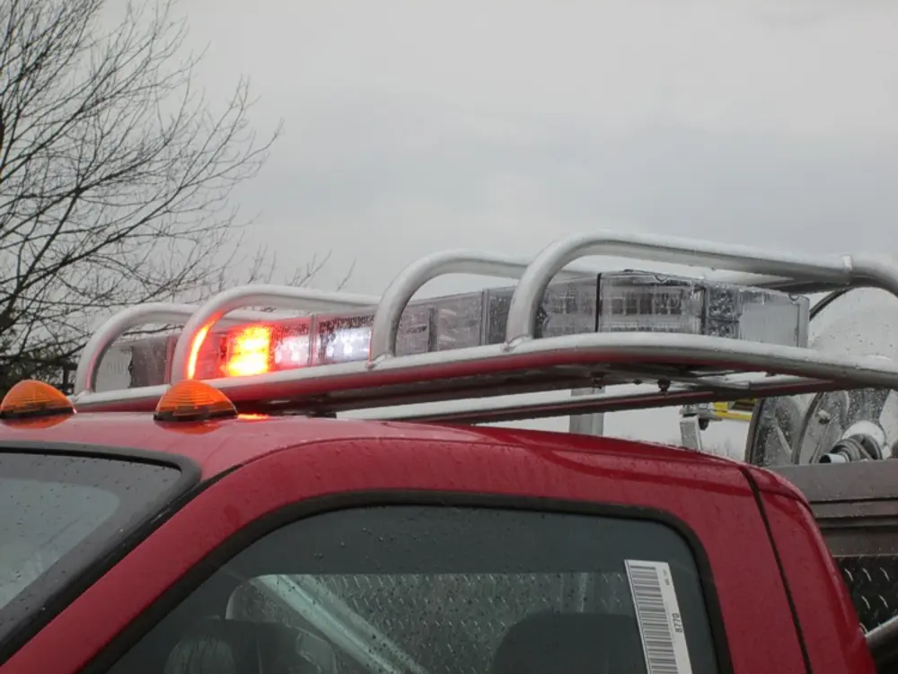 Exterior view of small fire truck showing cab, body compartments, and wheel/tire area.