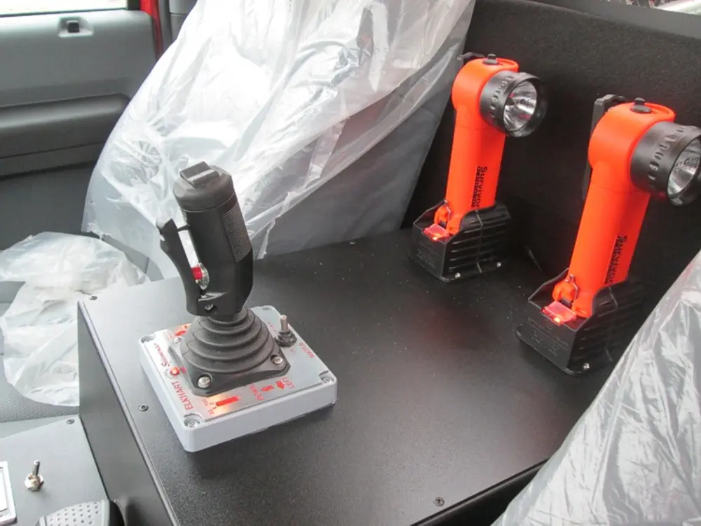 Exterior view of small fire truck showing cab, body compartments, and wheel/tire area.