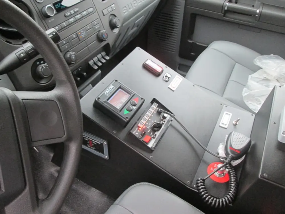 Exterior view of small fire truck showing cab, body compartments, and wheel/tire area.