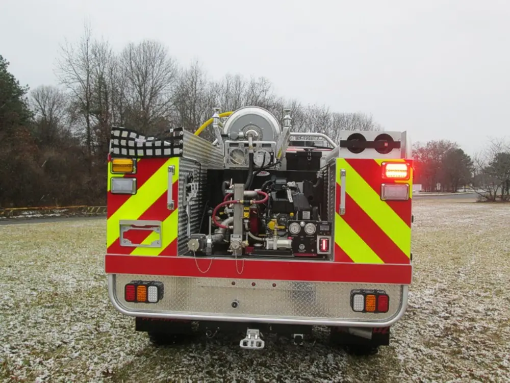 Exterior view of small fire truck showing cab, body compartments, and wheel/tire area.