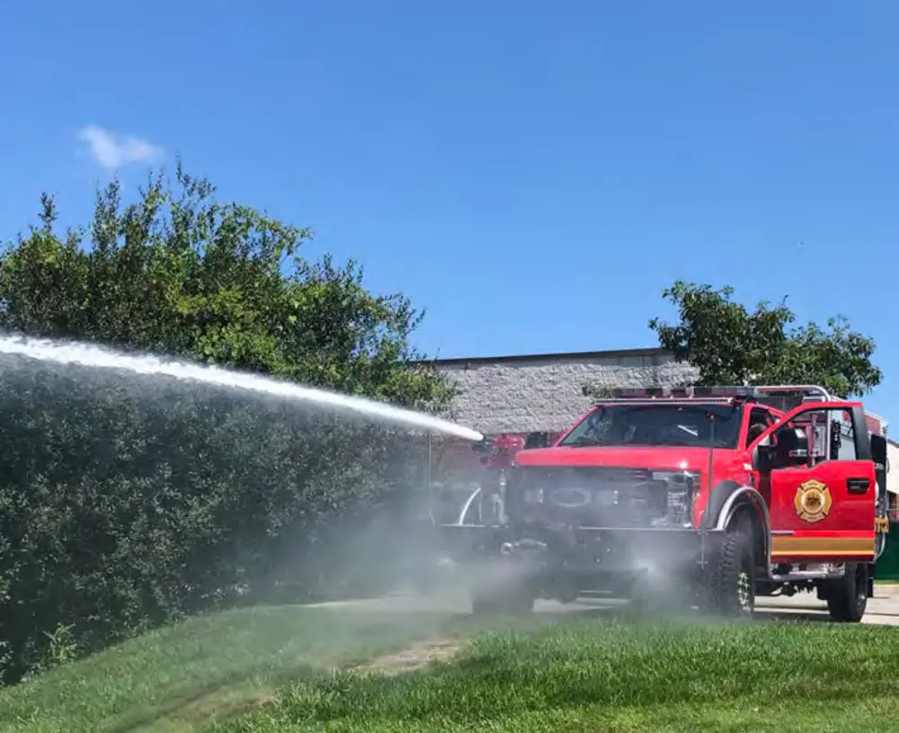Exterior view of small fire truck showing cab, body compartments, and wheel/tire area.