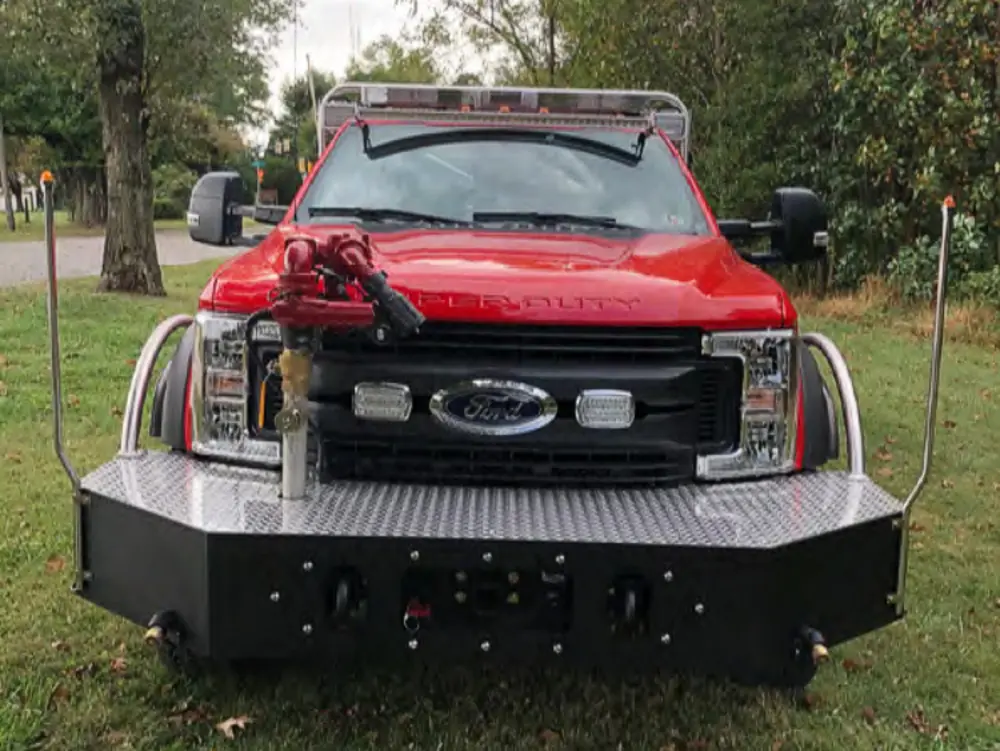 Exterior view of small fire truck showing cab, body compartments, and wheel/tire area.