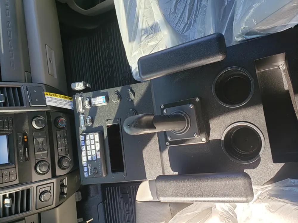 Exterior view of small fire truck showing cab, body compartments, and wheel/tire area.