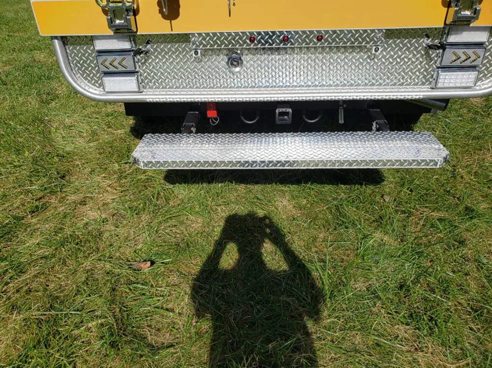 Exterior view of small fire truck showing cab, body compartments, and wheel/tire area.
