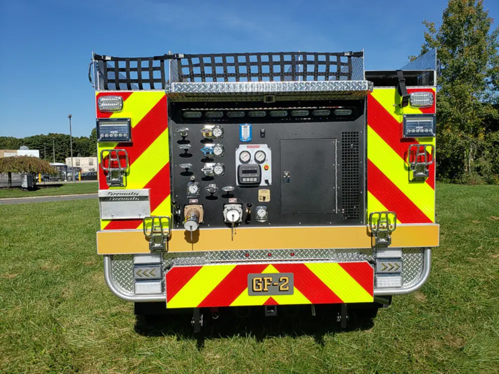 Exterior view of small fire truck showing cab, body compartments, and wheel/tire area.