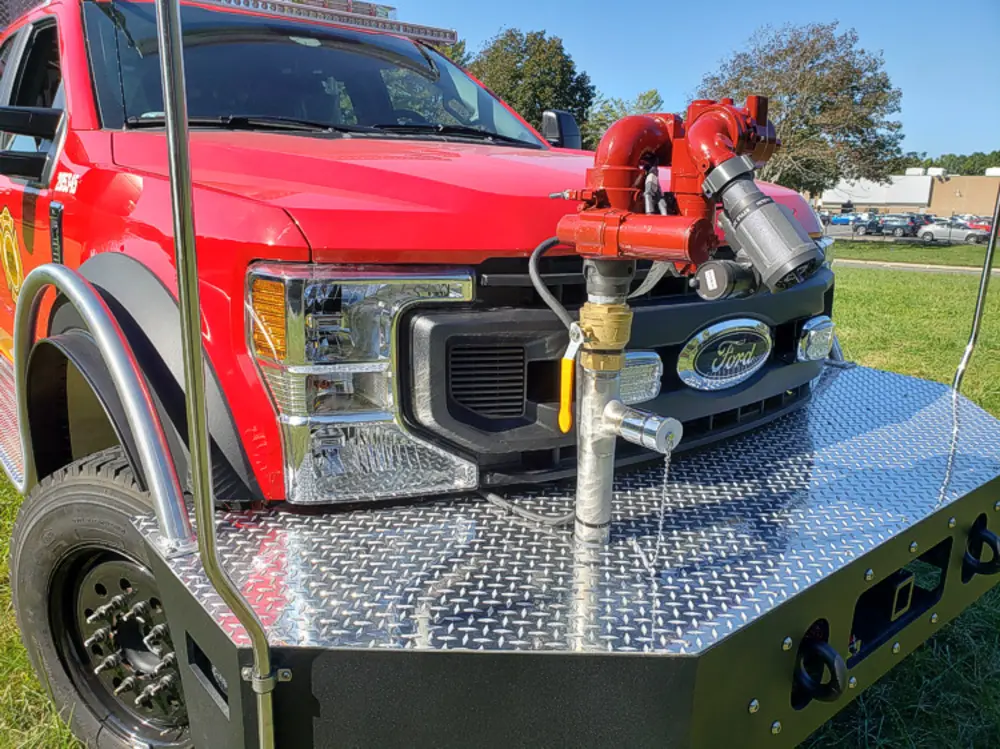 Exterior view of small fire truck showing cab, body compartments, and wheel/tire area.