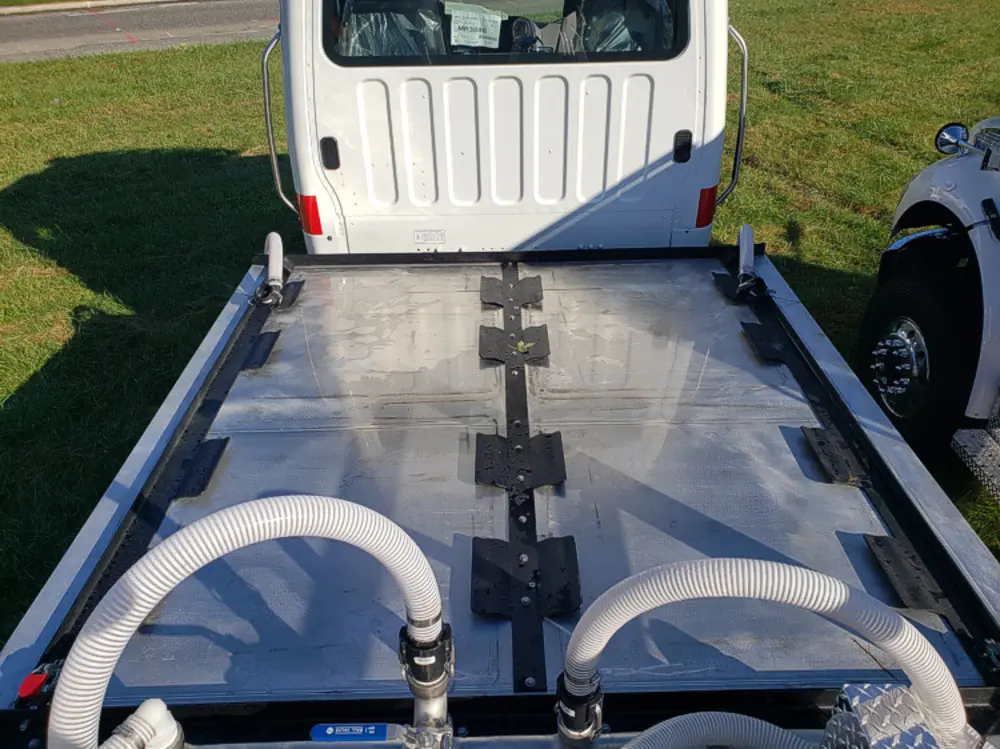 Exterior view of small fire truck showing cab, body compartments, and wheel/tire area.