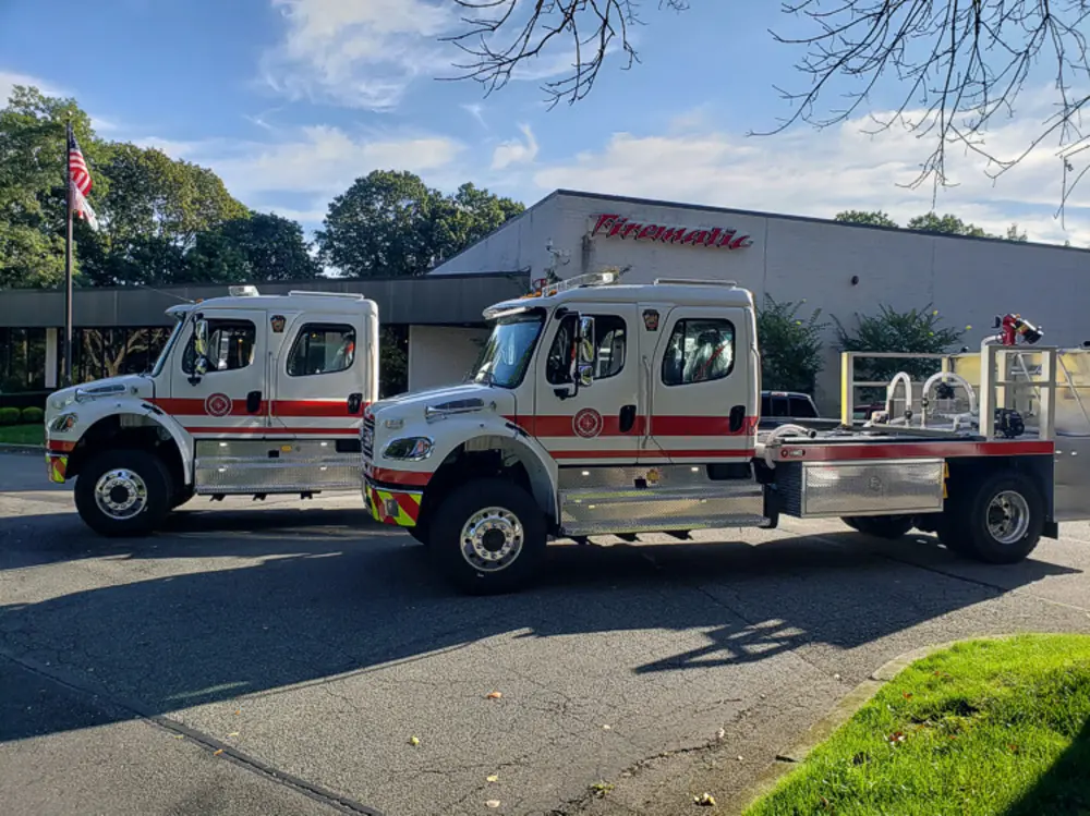 Exterior view of small fire truck showing cab, body compartments, and wheel/tire area.