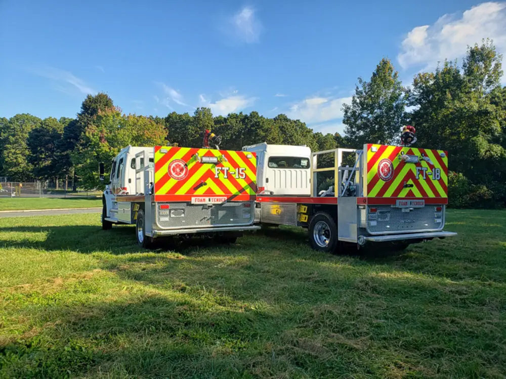 Exterior view of small fire truck showing cab, body compartments, and wheel/tire area.