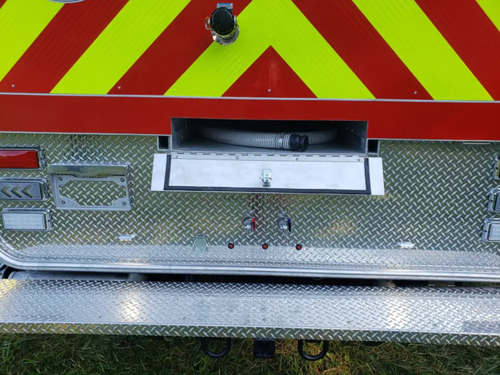 Exterior view of small fire truck showing cab, body compartments, and wheel/tire area.