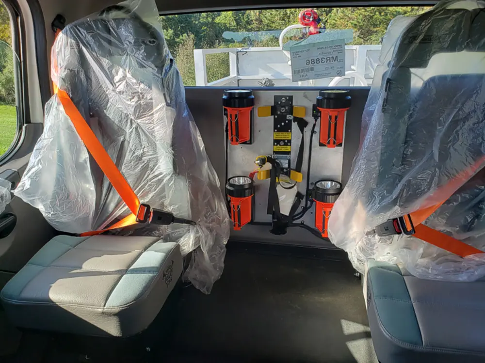 Exterior view of small fire truck showing cab, body compartments, and wheel/tire area.