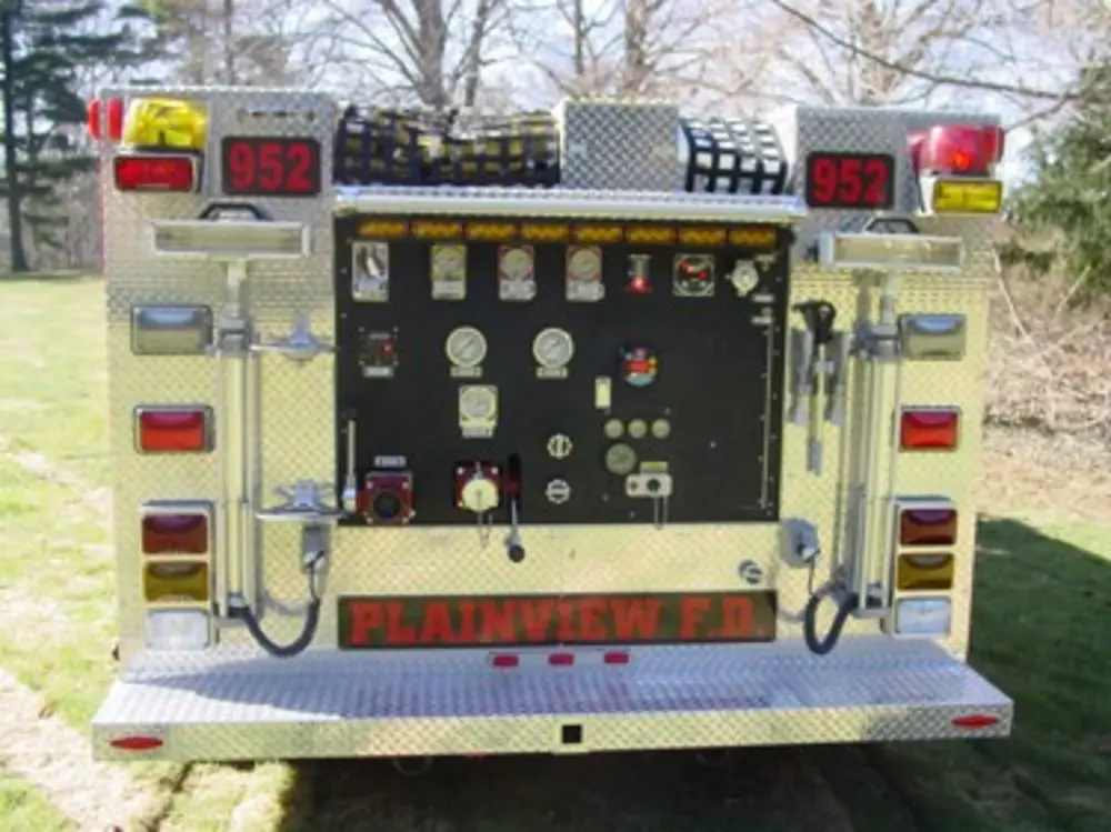 Exterior view of small fire truck showing cab, body compartments, and wheel/tire area.
