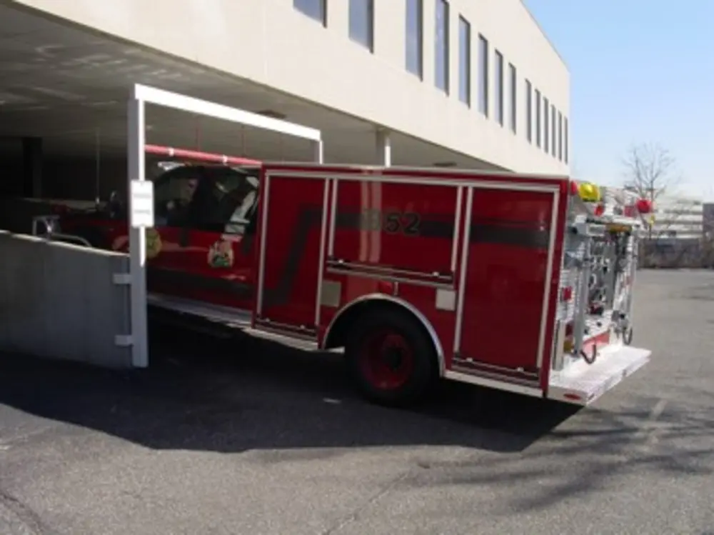 Exterior view of small fire truck showing cab, body compartments, and wheel/tire area.