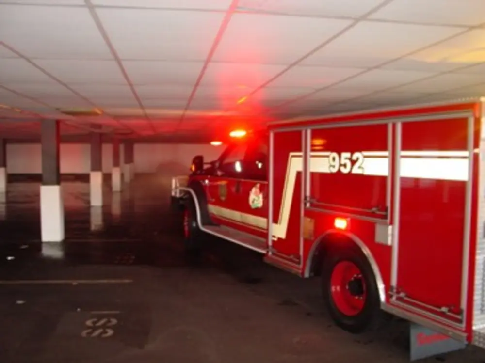 Exterior view of small fire truck showing cab, body compartments, and wheel/tire area.