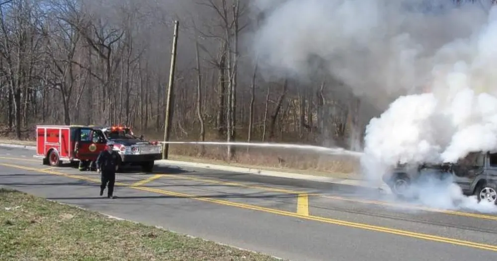 Exterior view of small fire truck showing cab, body compartments, and wheel/tire area.