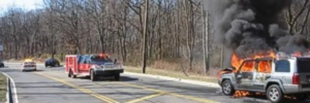 Exterior view of small fire truck showing cab, body compartments, and wheel/tire area.