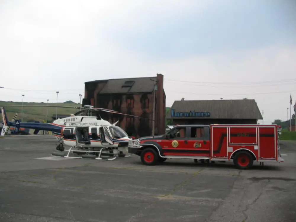 Exterior view of small fire truck showing cab, body compartments, and wheel/tire area.