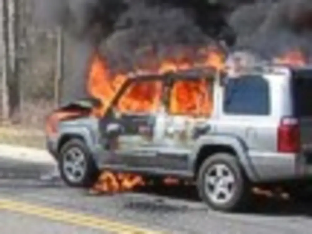 Exterior view of small fire truck showing cab, body compartments, and wheel/tire area.