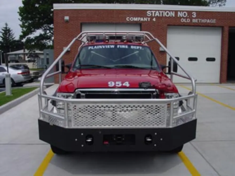 Exterior view of small fire truck showing cab, body compartments, and wheel/tire area.