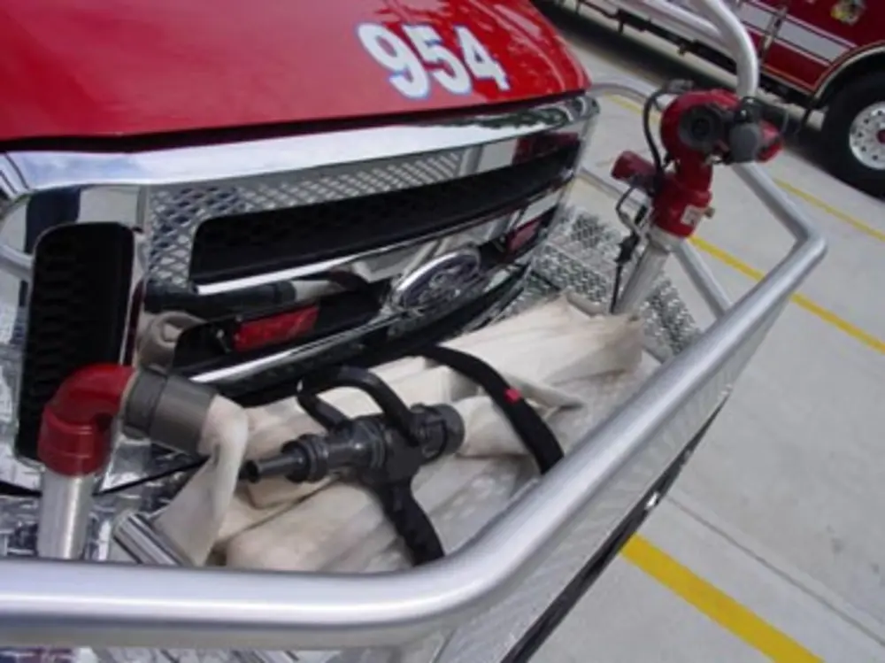 Exterior view of small fire truck showing cab, body compartments, and wheel/tire area.