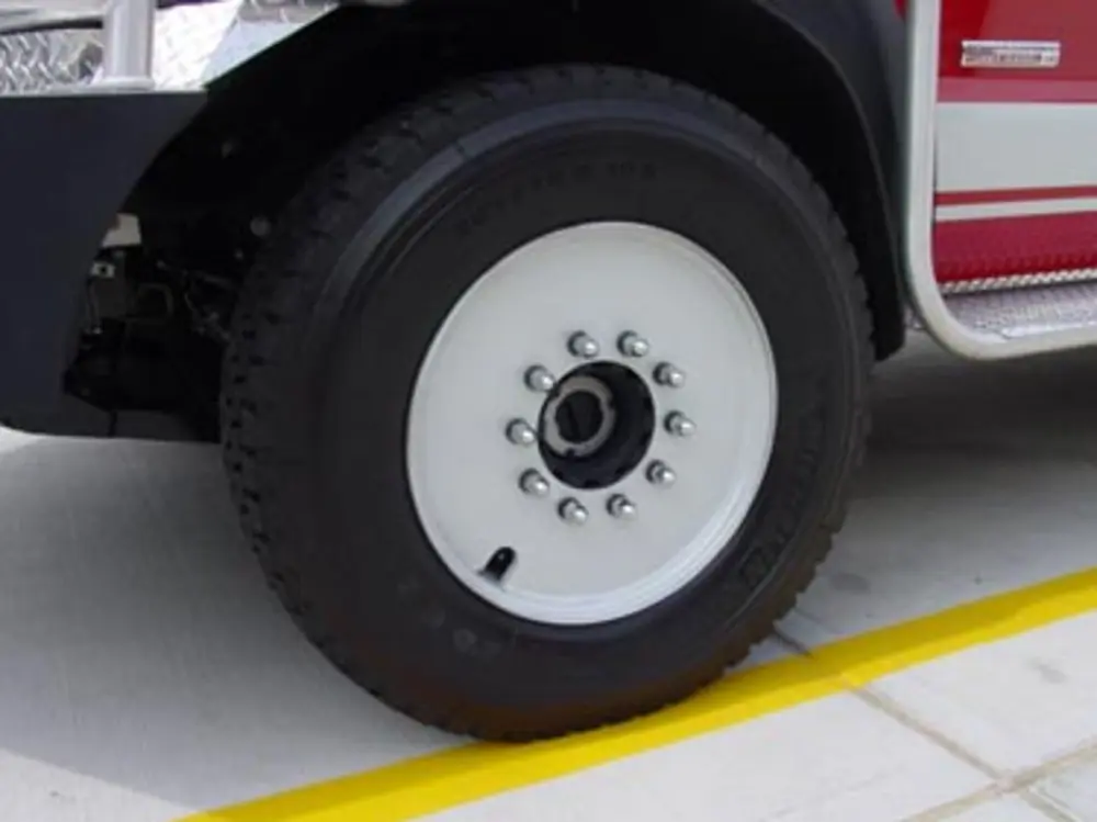 Exterior view of small fire truck showing cab, body compartments, and wheel/tire area.