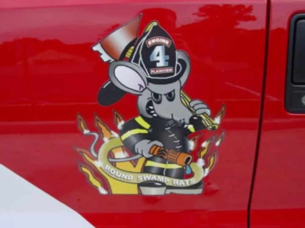 Exterior view of small fire truck showing cab, body compartments, and wheel/tire area.