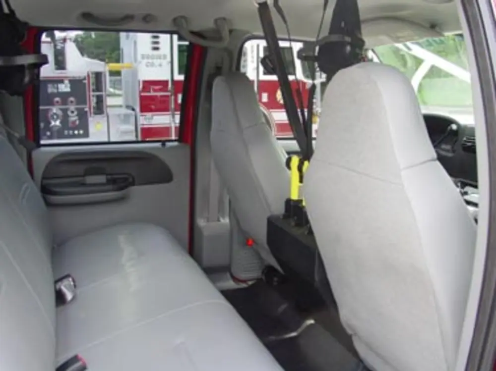 Exterior view of small fire truck showing cab, body compartments, and wheel/tire area.