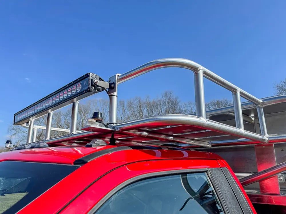 Exterior view of small fire truck showing cab, body compartments, and wheel/tire area.