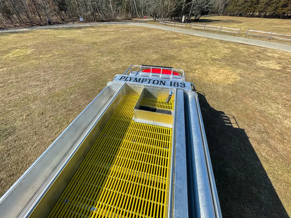 Exterior view of small fire truck showing cab, body compartments, and wheel/tire area.