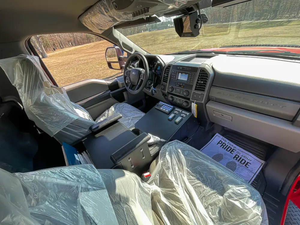 Exterior view of small fire truck showing cab, body compartments, and wheel/tire area.
