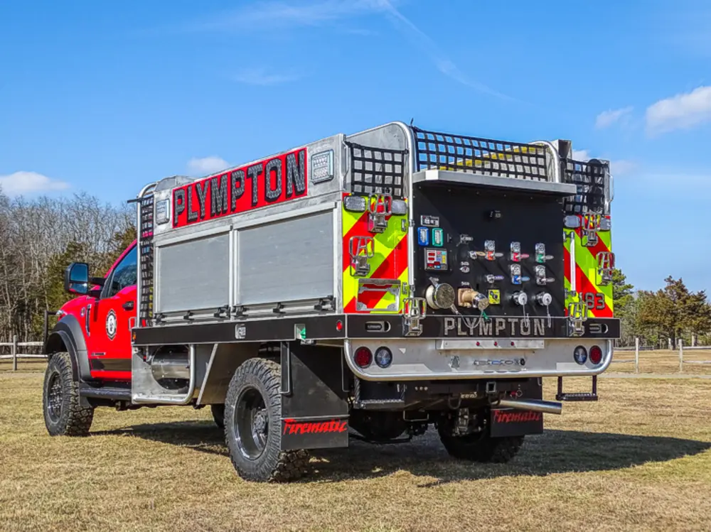Exterior view of small fire truck showing cab, body compartments, and wheel/tire area.