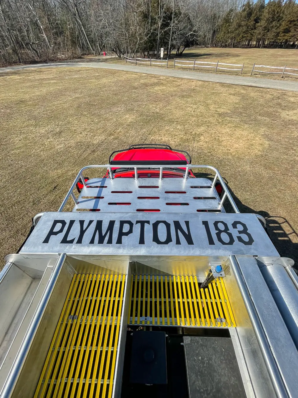 Exterior view of small fire truck showing cab, body compartments, and wheel/tire area.