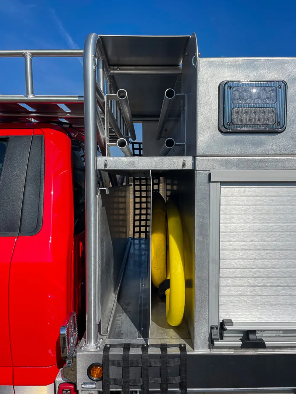 Exterior view of small fire truck showing cab, body compartments, and wheel/tire area.