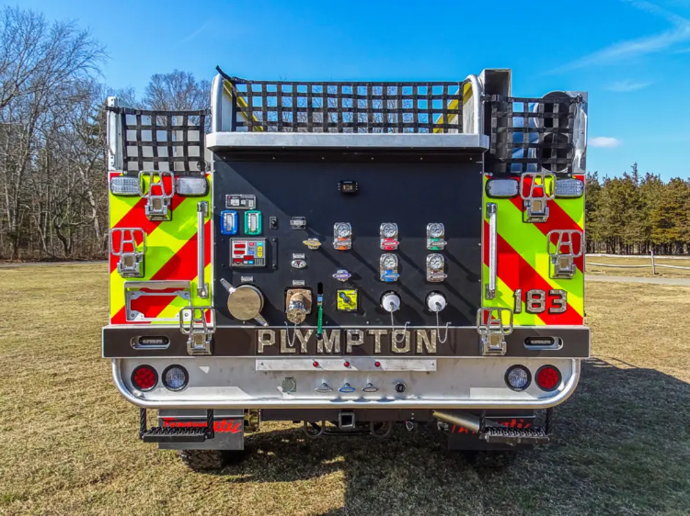 Exterior view of small fire truck showing cab, body compartments, and wheel/tire area.
