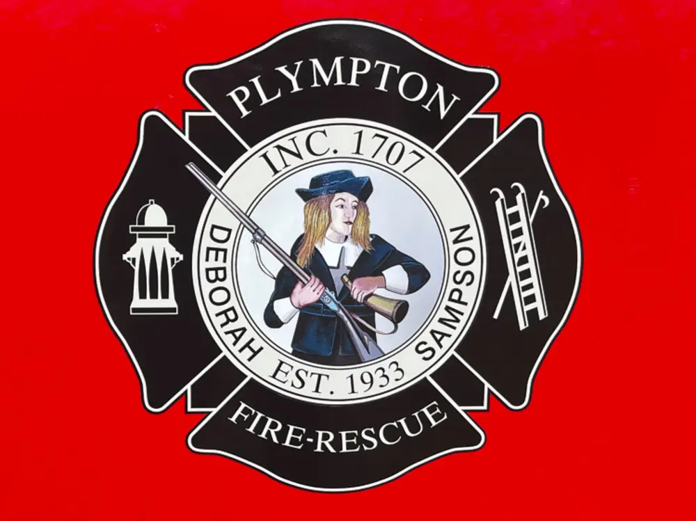 Exterior view of small fire truck showing cab, body compartments, and wheel/tire area.