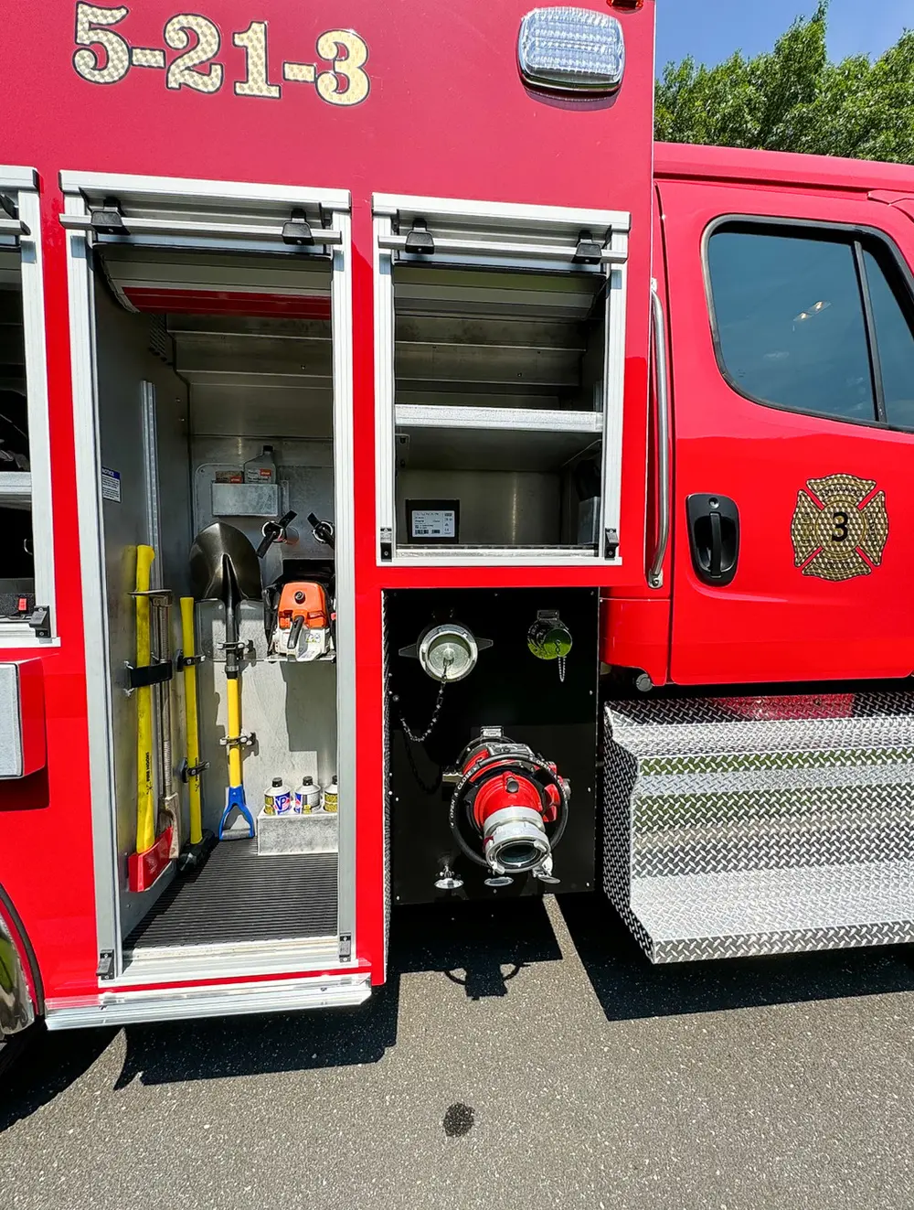 Exterior view of small fire truck showing cab, body compartments, and wheel/tire area.