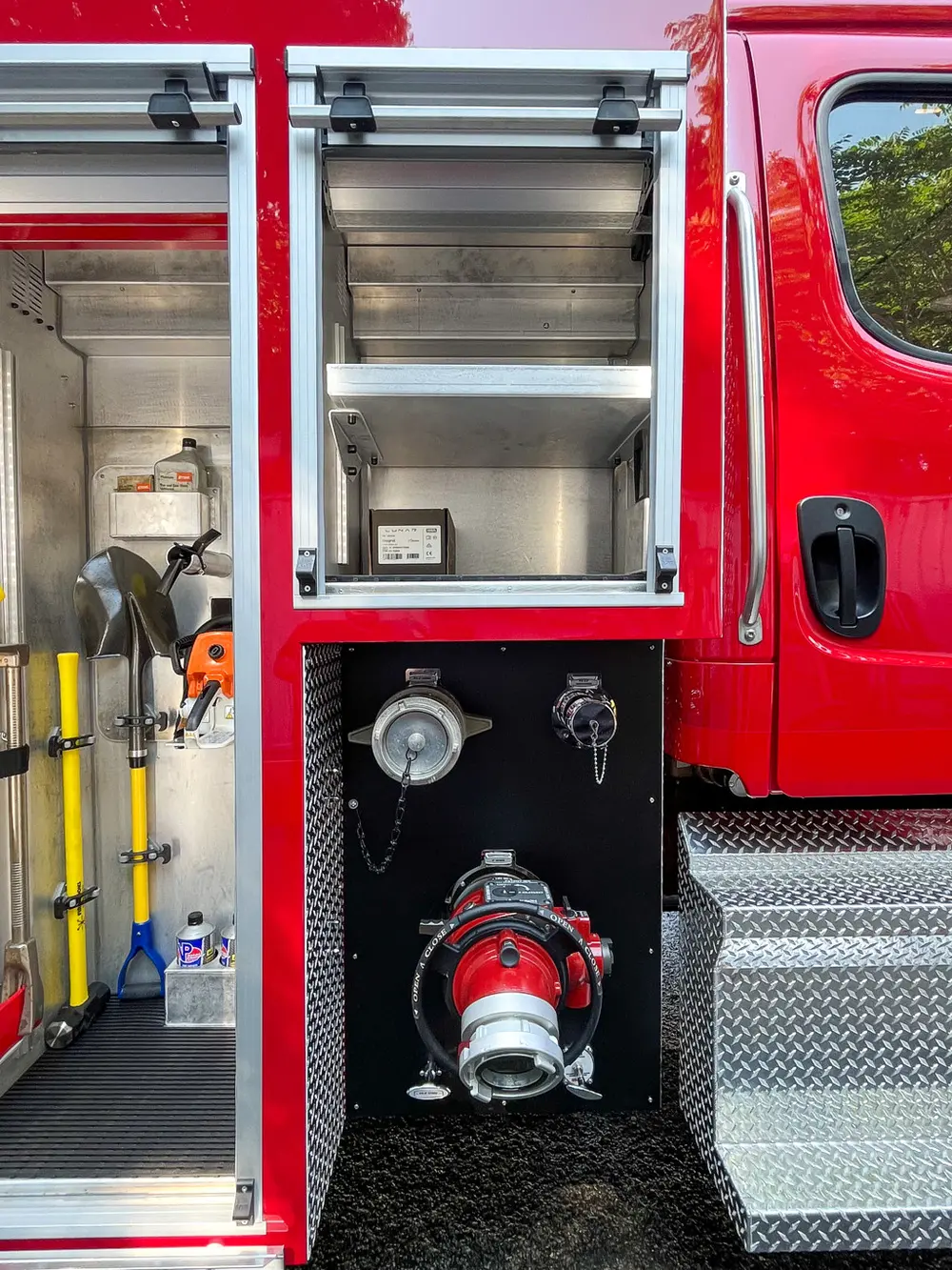 Exterior view of small fire truck showing cab, body compartments, and wheel/tire area.