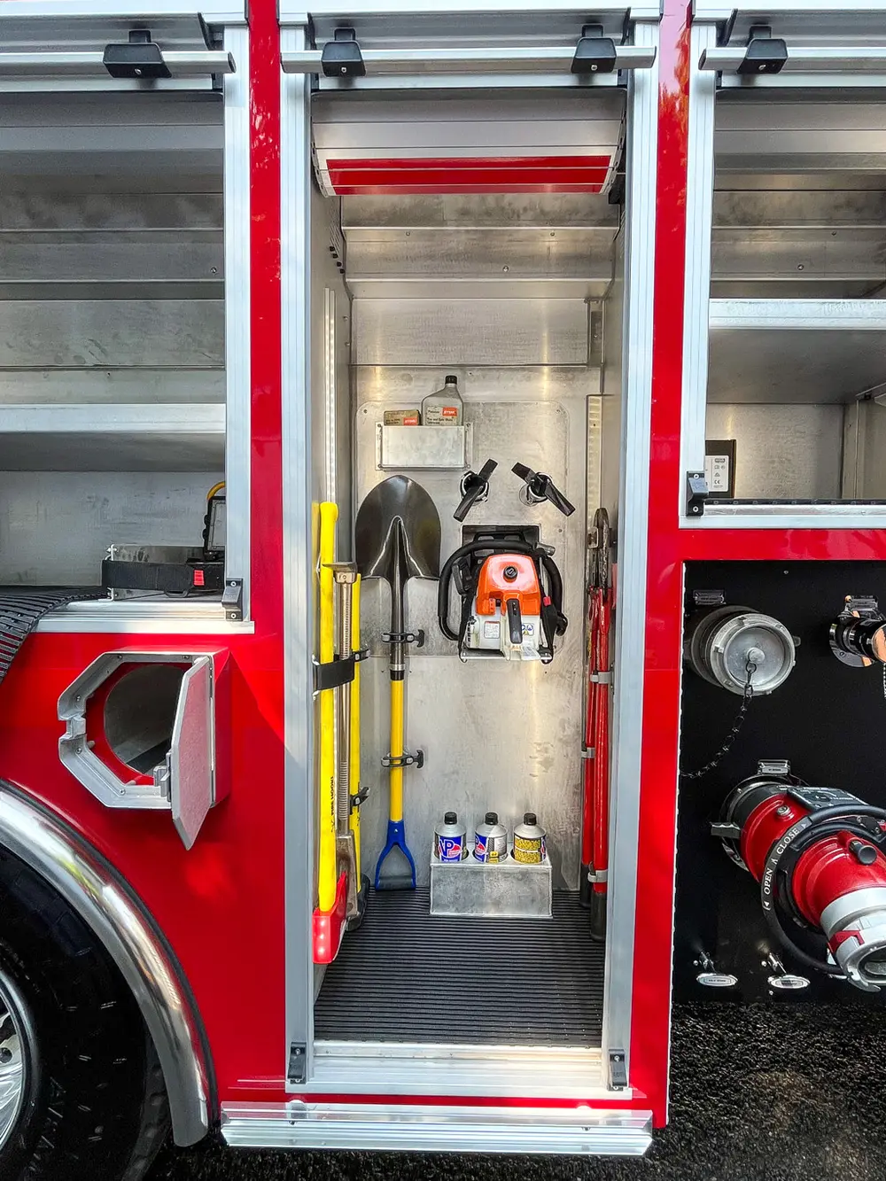Exterior view of small fire truck showing cab, body compartments, and wheel/tire area.
