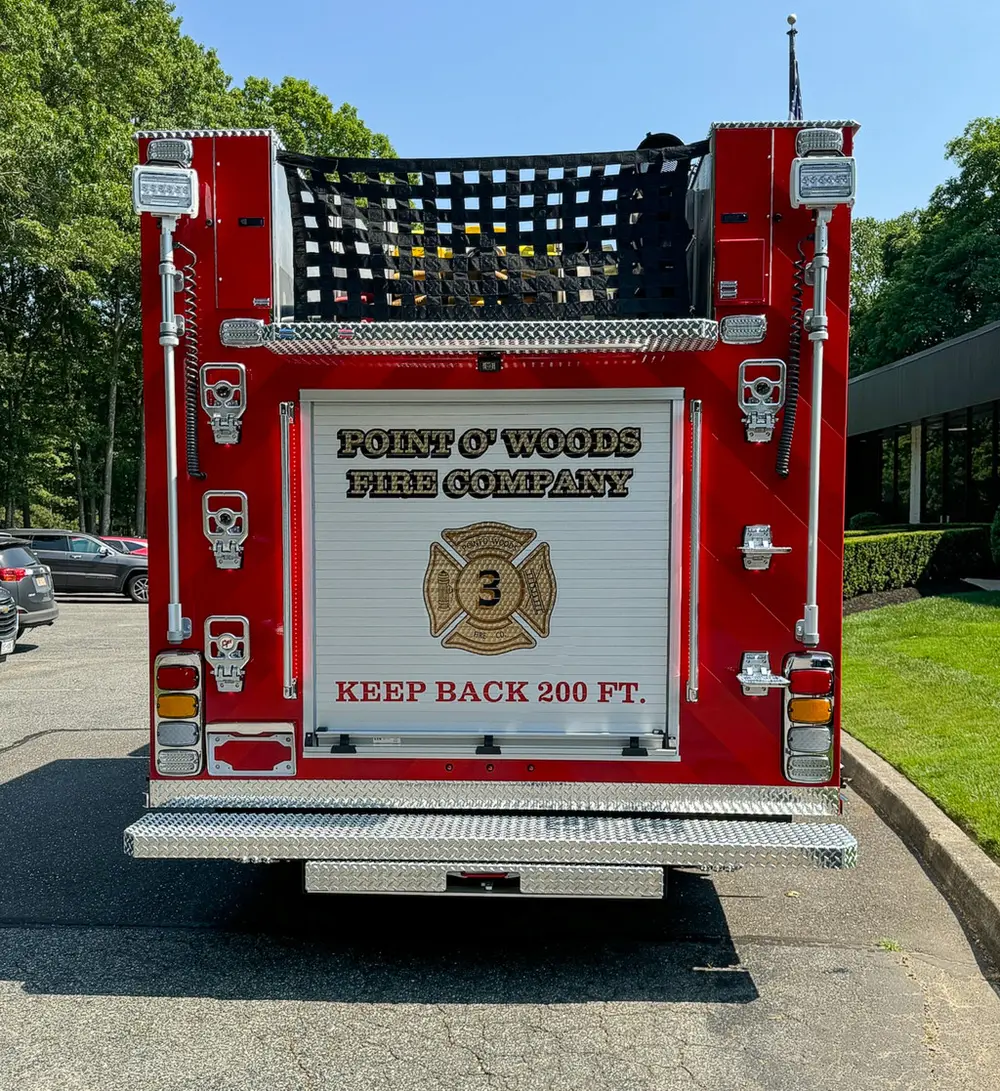 Exterior view of small fire truck showing cab, body compartments, and wheel/tire area.