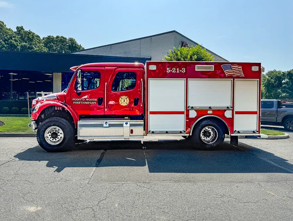 Exterior view of small fire truck showing cab, body compartments, and wheel/tire area.