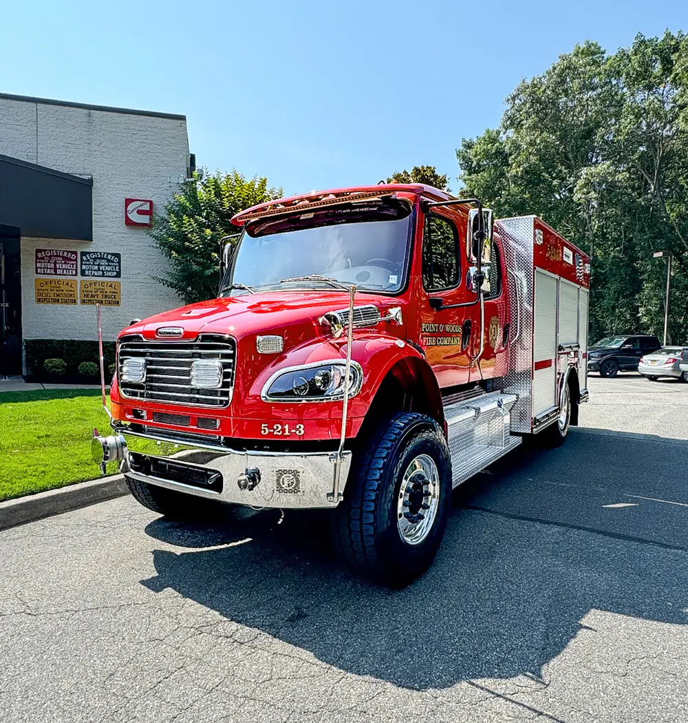 Exterior view of small fire truck showing cab, body compartments, and wheel/tire area.