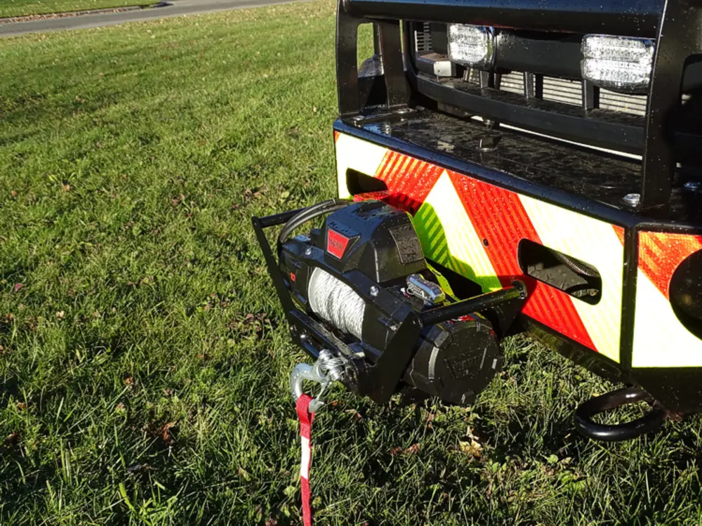 Exterior view of small fire truck showing cab, body compartments, and wheel/tire area.