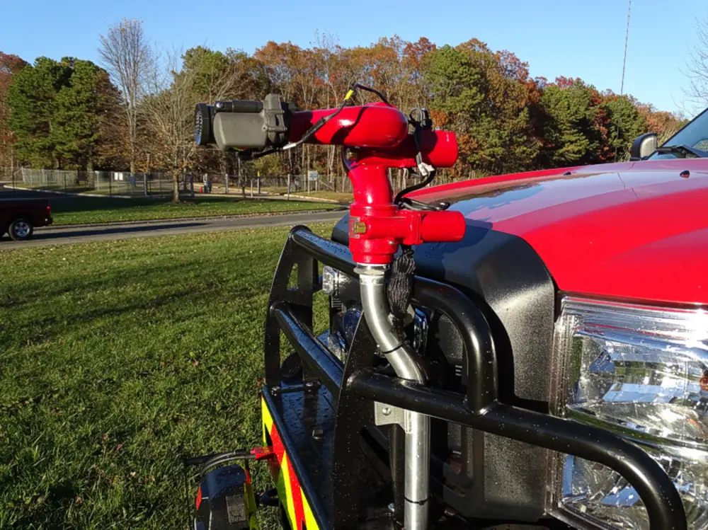 Exterior view of small fire truck showing cab, body compartments, and wheel/tire area.
