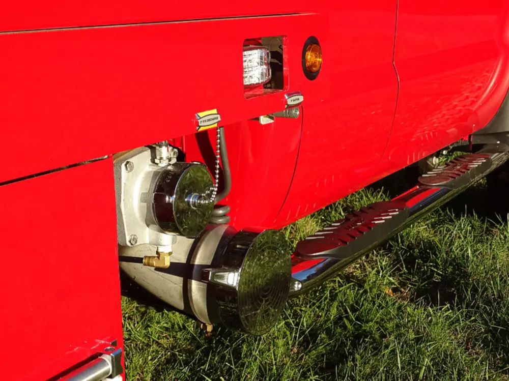 Exterior view of small fire truck showing cab, body compartments, and wheel/tire area.