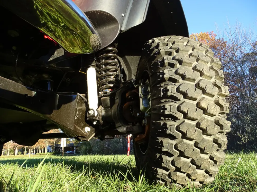 Exterior view of small fire truck showing cab, body compartments, and wheel/tire area.
