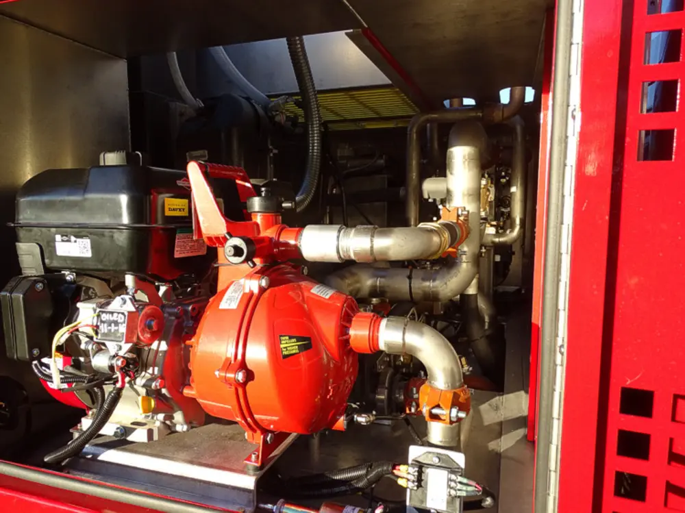 Exterior view of small fire truck showing cab, body compartments, and wheel/tire area.