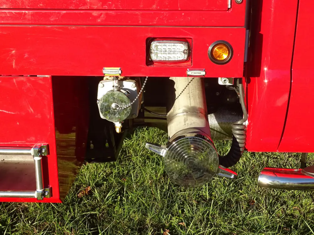 Exterior view of small fire truck showing cab, body compartments, and wheel/tire area.