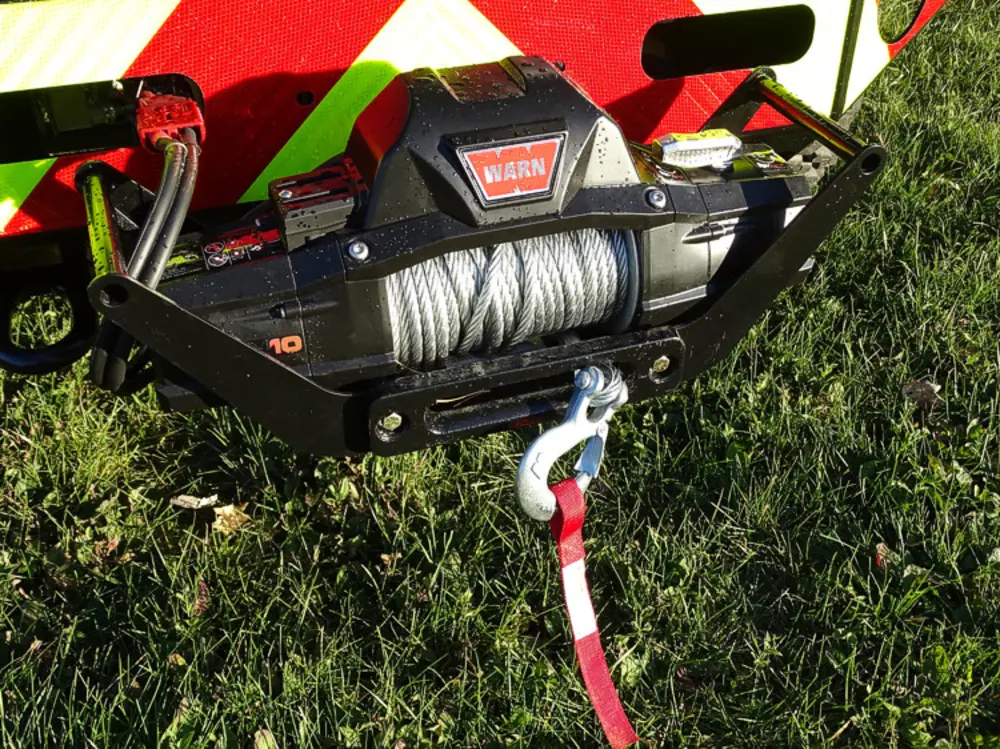 Exterior view of small fire truck showing cab, body compartments, and wheel/tire area.