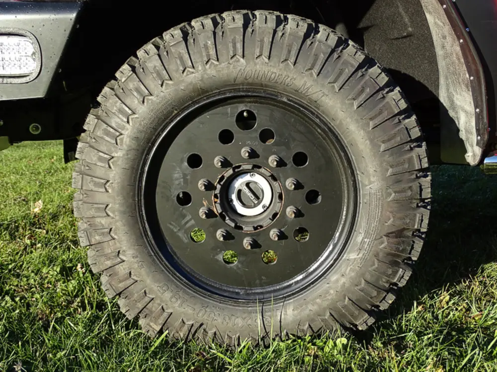 Exterior view of small fire truck showing cab, body compartments, and wheel/tire area.